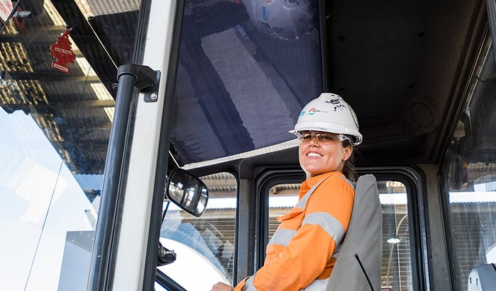 An apprentice, sitting in the drivers seat of a heavy vehicle